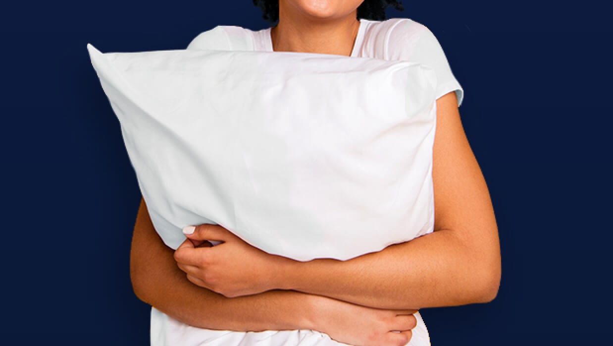 Persona abrazando una almohada alrededor de su pecho