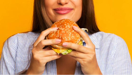 Mujer comiendo una hamburguesa con queso